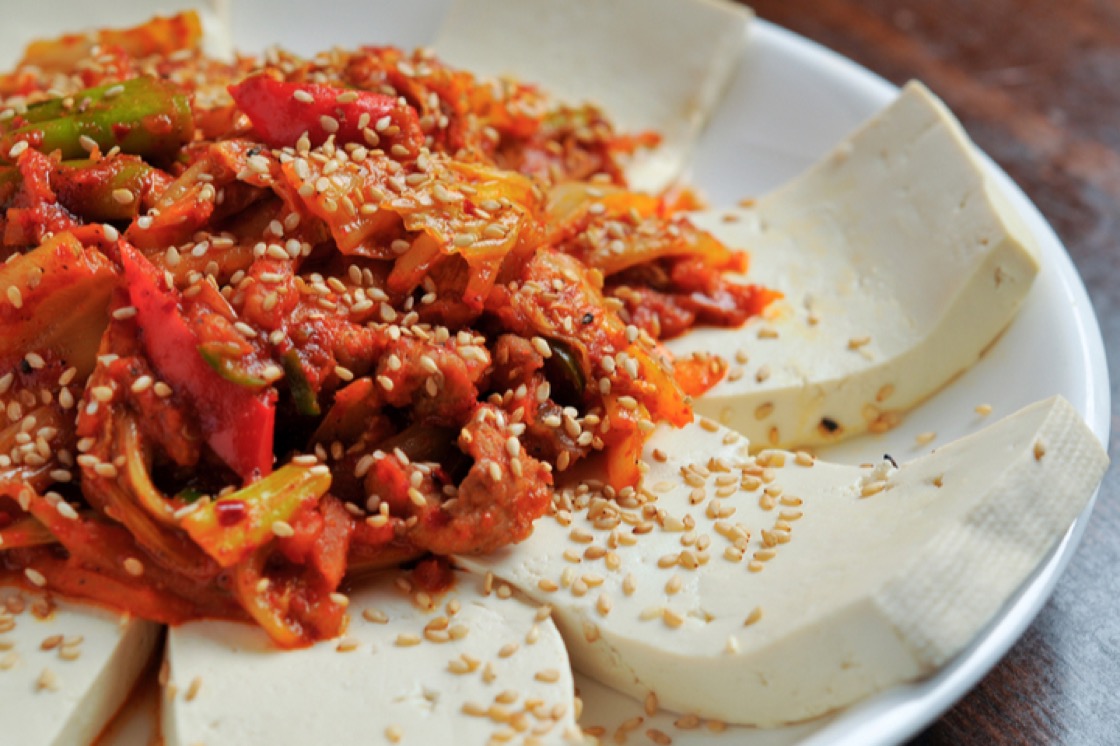 A healthy appetizer of tofu topped with kimchi and white sesame seeds.