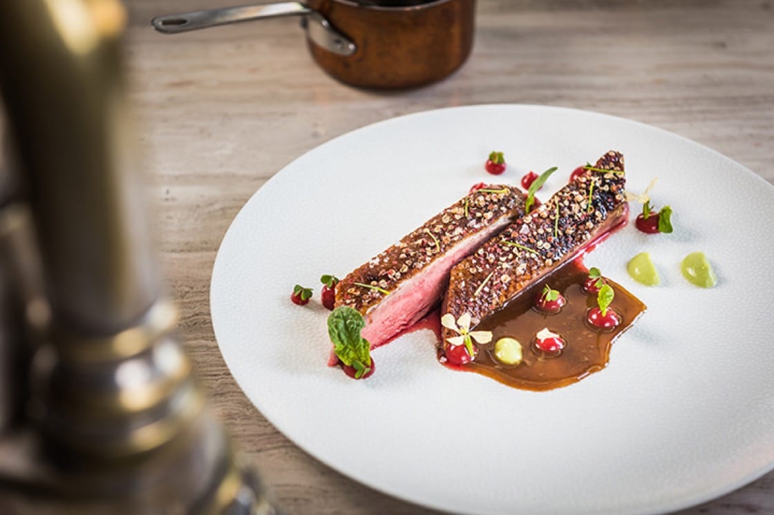 Bresca's glazed, spice-crusted duck breast in sauce is accompanied by an apple salad, oat milk bread and a savory tart of the leg and thighs with apple mostarda. (Photo by Rey Lopez.)