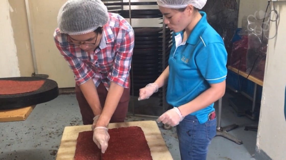  About 40 meat sheets are stacked in a pile before they are chopped evenly into nine squares. 