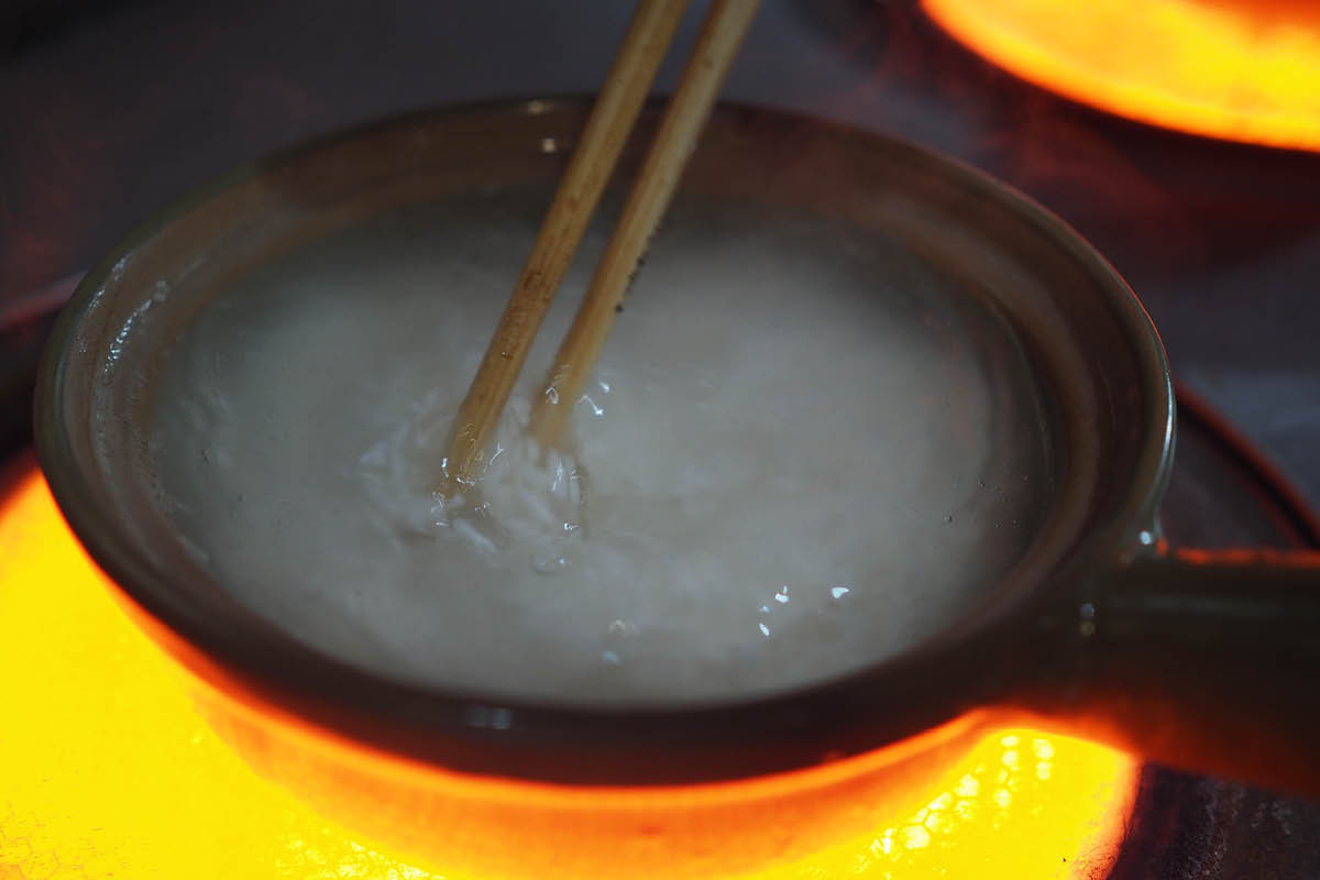 In a ceramic claypot, white rice and water are brought to the boil, stirred and drained, then covered with all sorts of toppings.