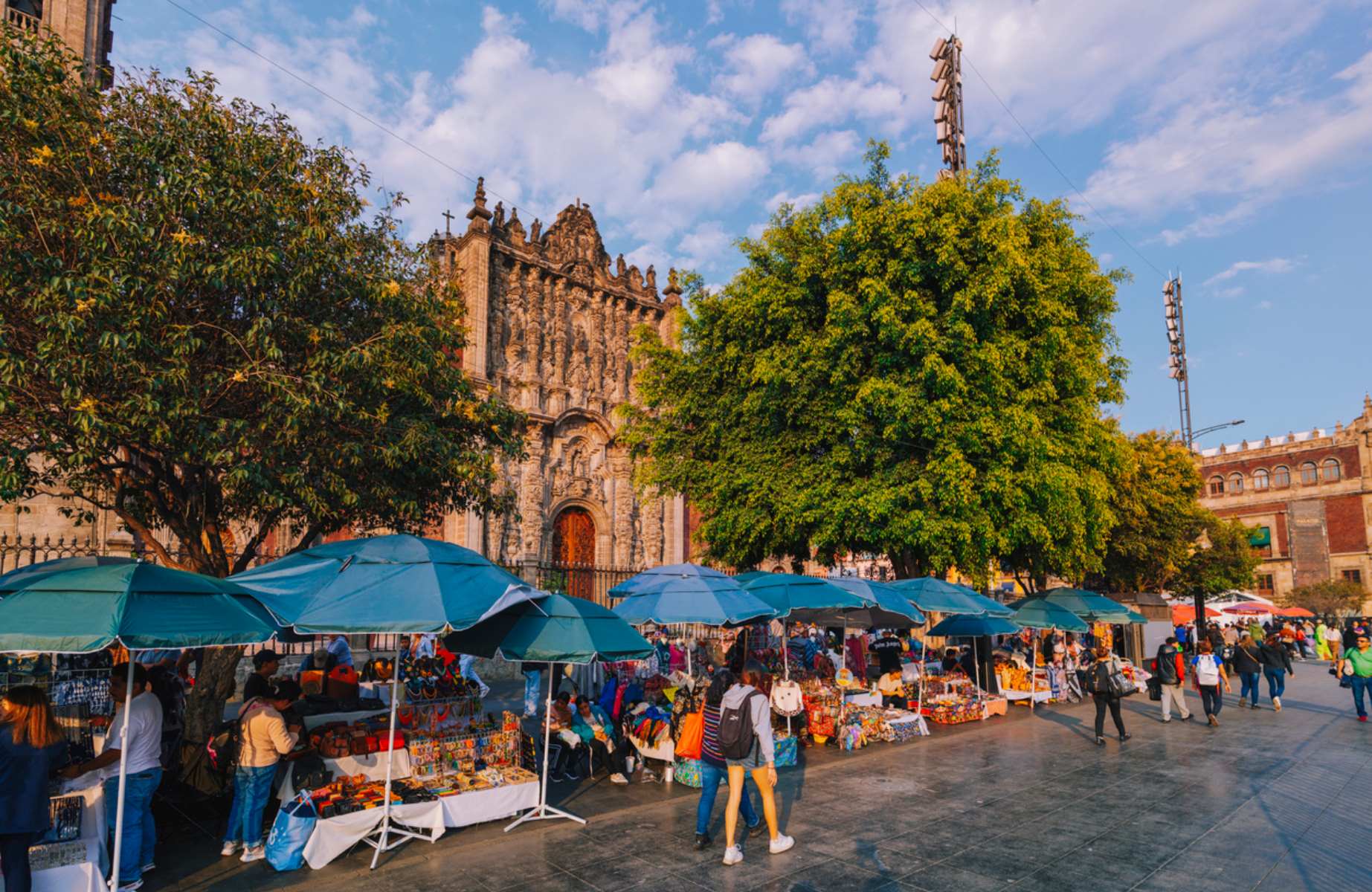 A bustling street market thrives in front of the ornate façade of the Mexico City Metropolitan Cathedral under a bright afternoon sky ©pawel.gaul/iStock