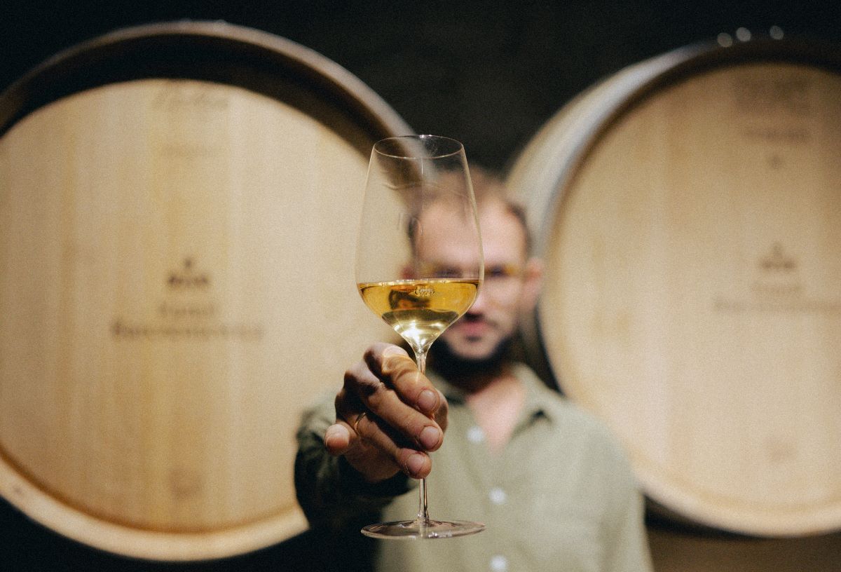 Kamil Barczentewicz with a glass of Chardonnay in front of the oak barrels © Winnica Kamil Barczentewicz