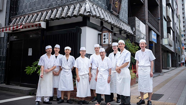 After the lunch service, Kanemoto Kenjiro (fourth from right) stands with sixth-generation Noboru (fifth from right), seventh-generation Kentaro (second from right), and other staff in front of the restaurant 