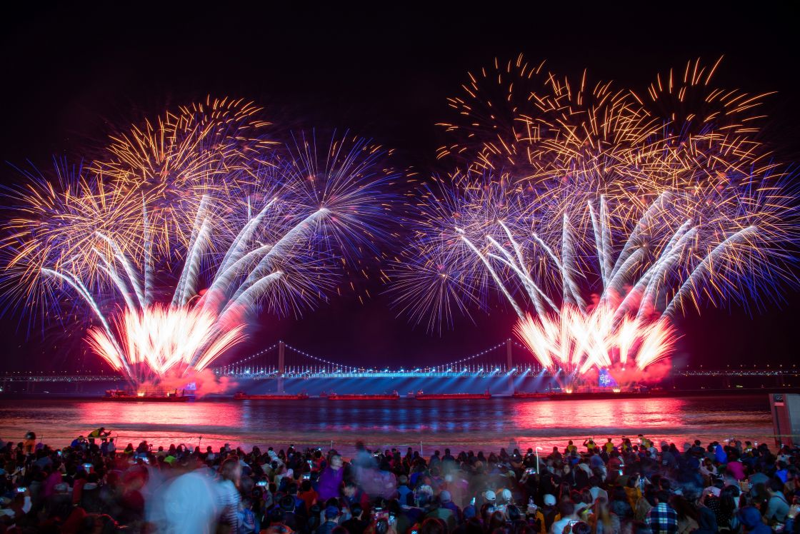 Crowds gather on Gwangalli Beach to watch the Busan Fireworks Festival unfold against the backdrop of Gwangandaegyo Bridge.