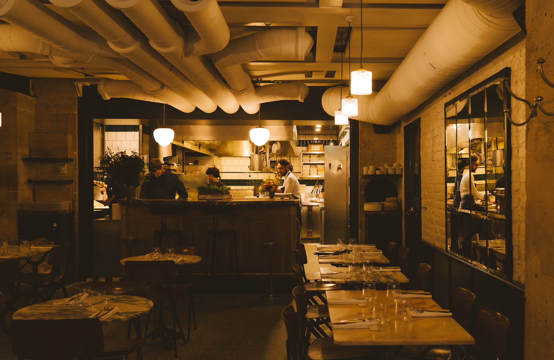 The alluring, low-lit dining room and kitchen of Semilla restaurant, Paris. ©Joann Pai/The MICHELIN Guide