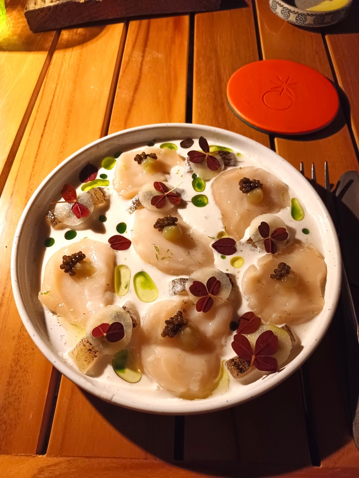 A generous portion of scallops topped with caviar swim in a tasty spring onion buttermilk. Image credit: The MICHELIN Guide