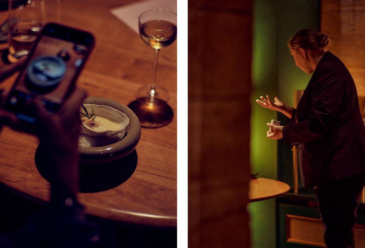 Another signature dish, Irish Mór oyster from the embers with moyga and elderflower, being photographed and team member Sabrina Kirch interacting with guests. © Wim Jansen/The MICHELIN Guide