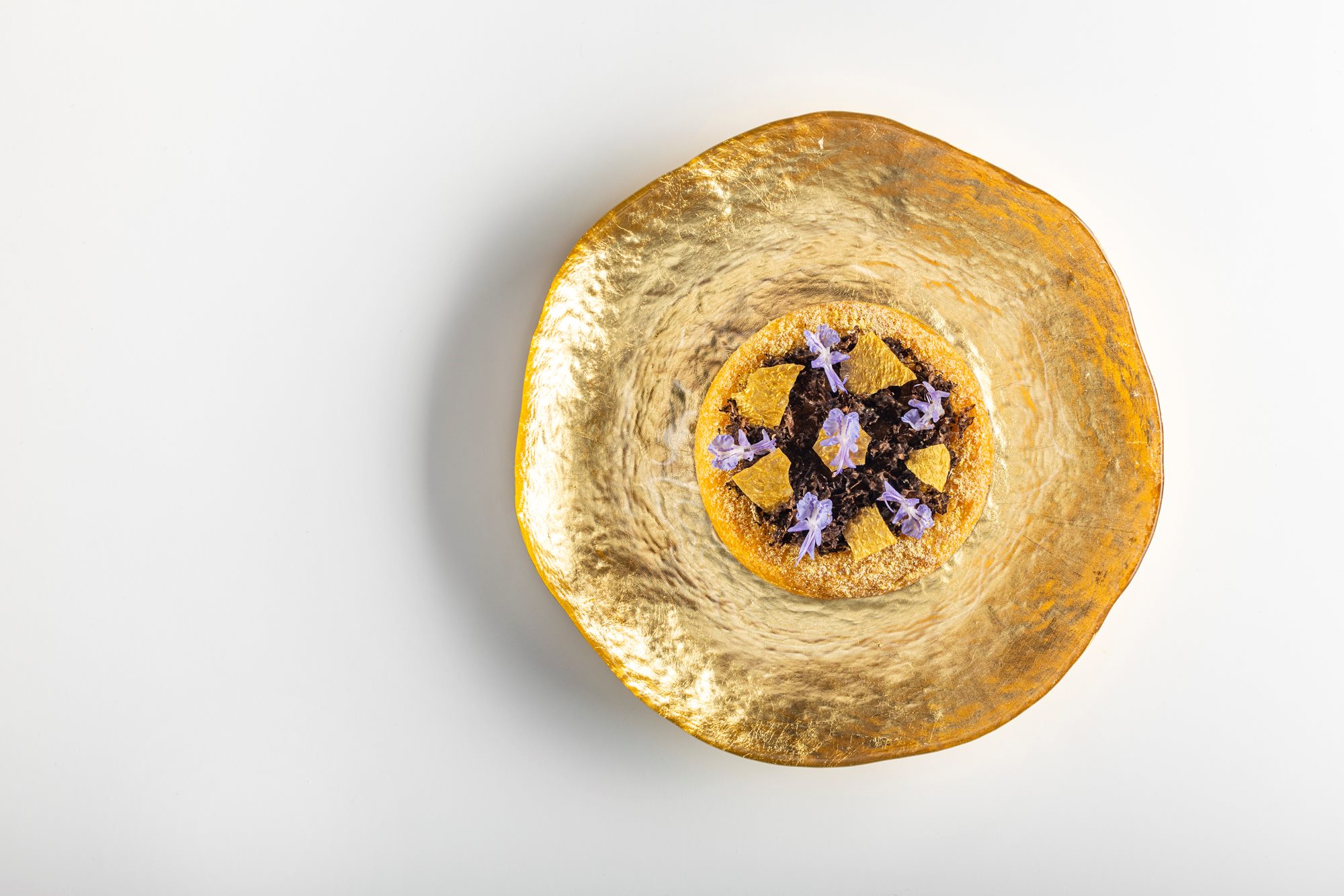 Coca farcida de maíz, trompetas y trufa: un consomé caliente y cremoso, diseñado por el Chef Mentor 2026: Quique Dacosta. © Restaurante Quique Dacosta