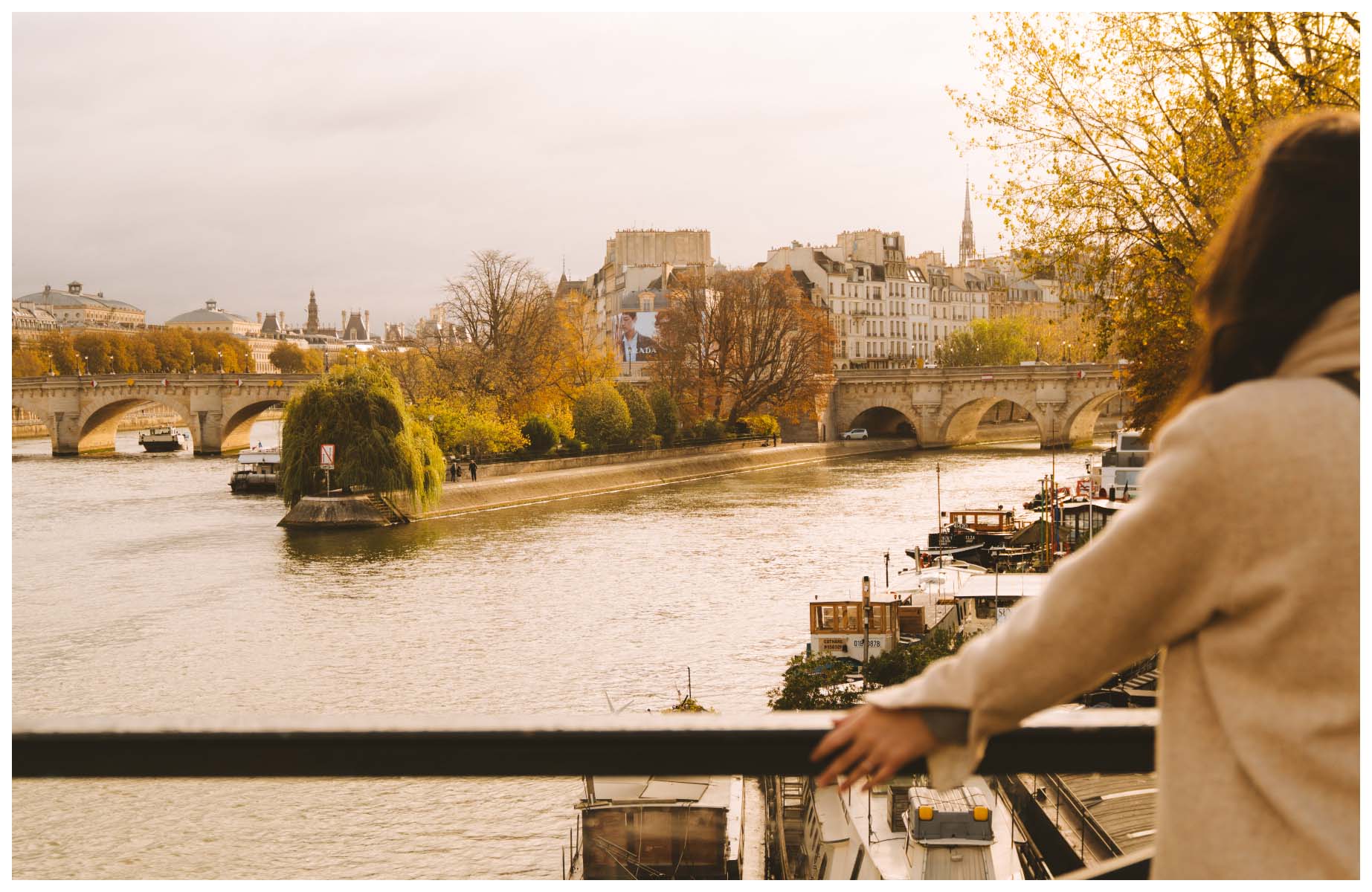 Journalist and author Lindsey Tramuta looking out at the banks of the Seine from a bridge and the tip of the Île de la Cité beyond. © Joann Pai/The MICHELIN Guide