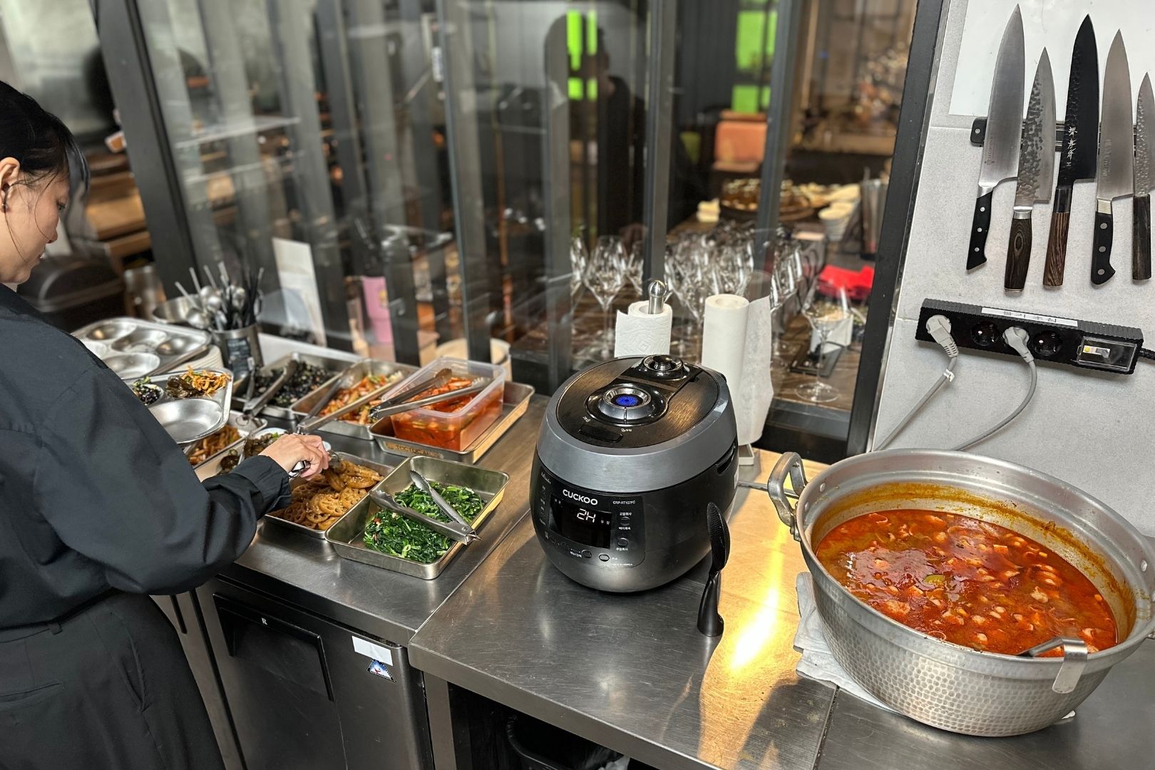 A member of the 7th Door team helps herself to home-style ‘banchan’ side dishes, rice and soup in the kitchen. © The MICHELIN Guide