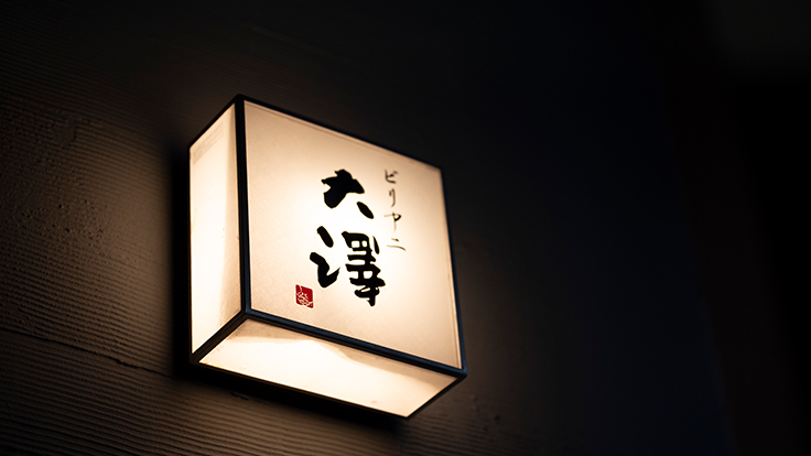 With no street-level signage, an illuminated “Biriyani Osawa” sign appears partway down the staircase.  © Hisashi Yoshino / the MICHELIN Guide