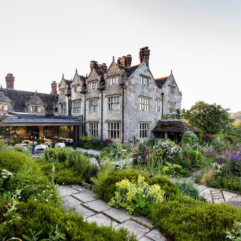 Gravetye Manor's imposing stone exterior, light-filled dining room and well-kept gardens. © Gravetye Manor