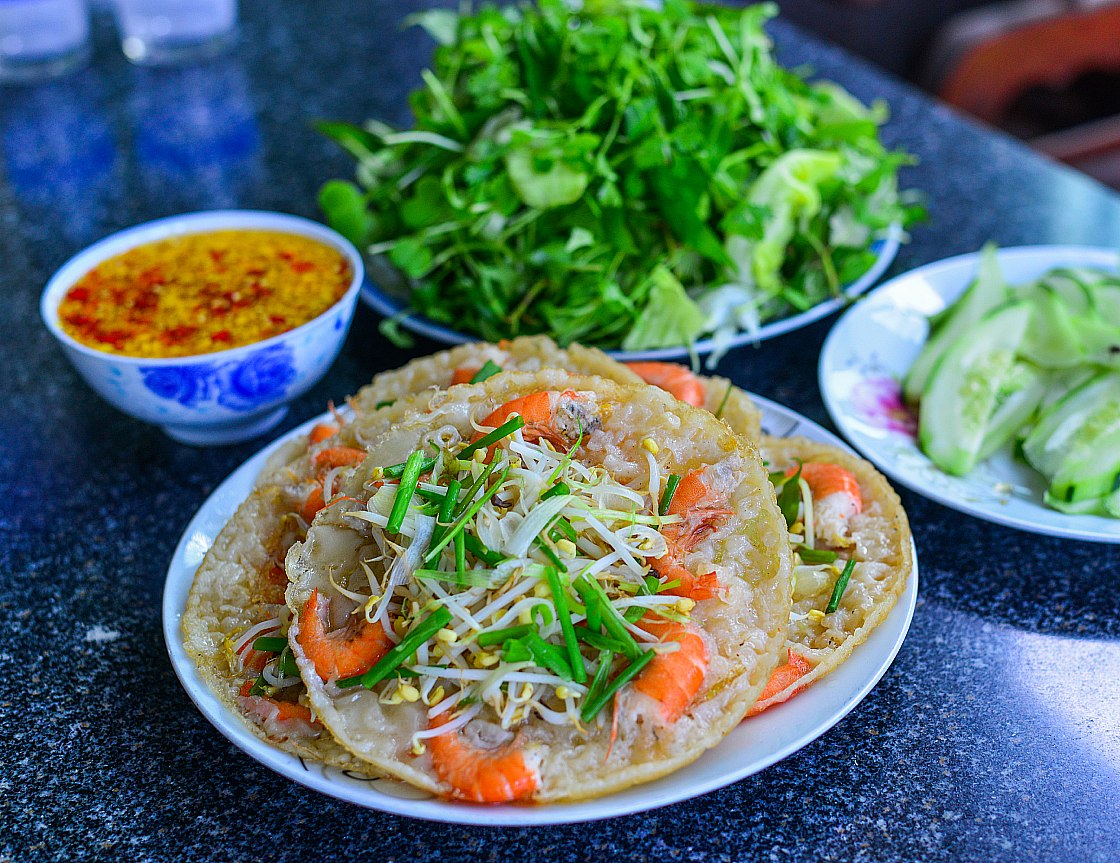 Fresh vegetables and seafood are added to this crispy bánh xèo at a local restaurant in Vietnam. © Shutterstock