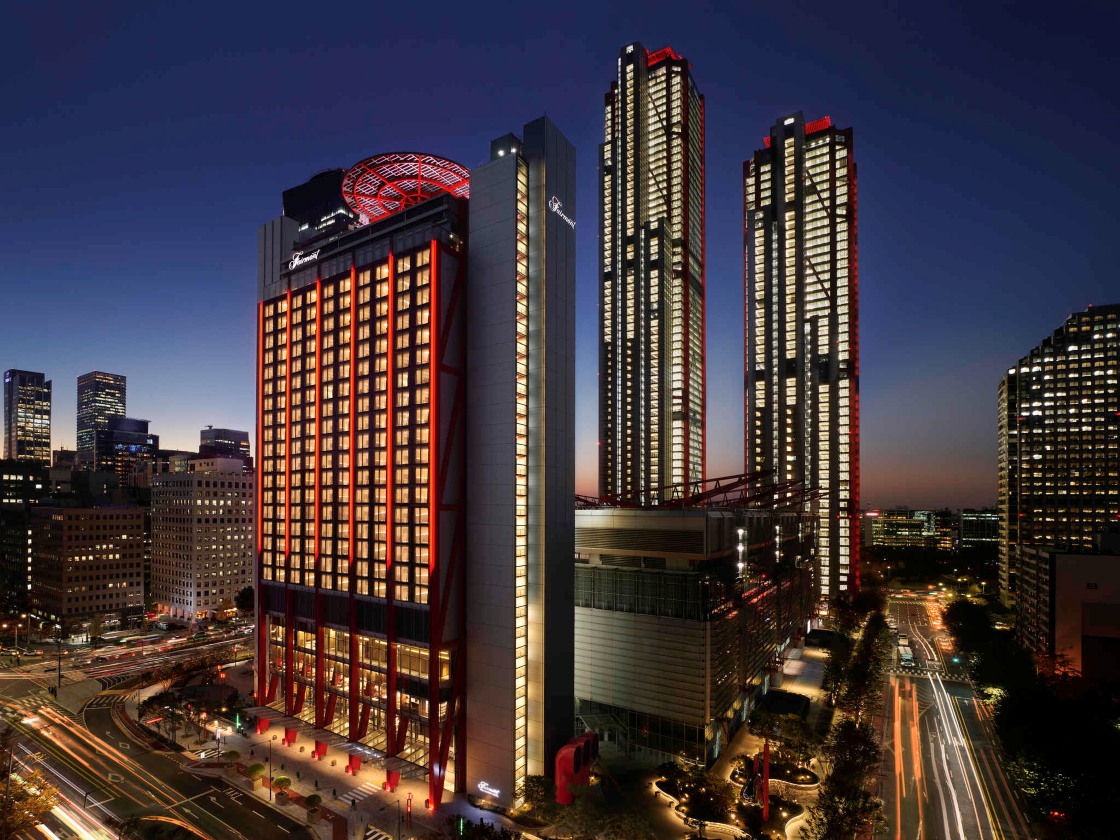 Fairmont Ambassador Seoul rises above Yeouido’s financial district, its striking façade illuminated against the city’s evening skyline. © Fairmont Ambassador Seoul