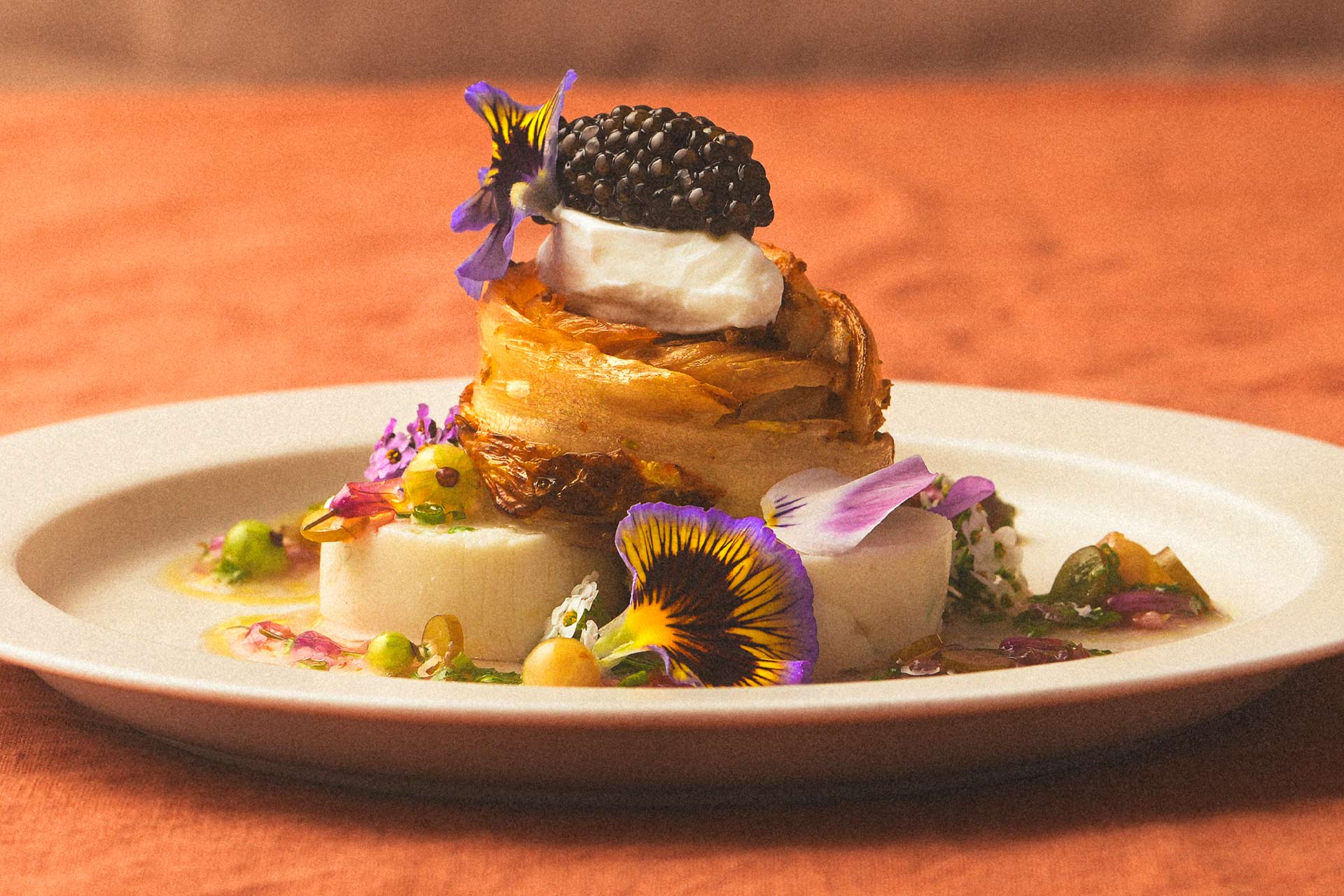 Purple and yellow flowers enhance a plate of elderflower cabbage halibut. © Hakan Burcuoglu