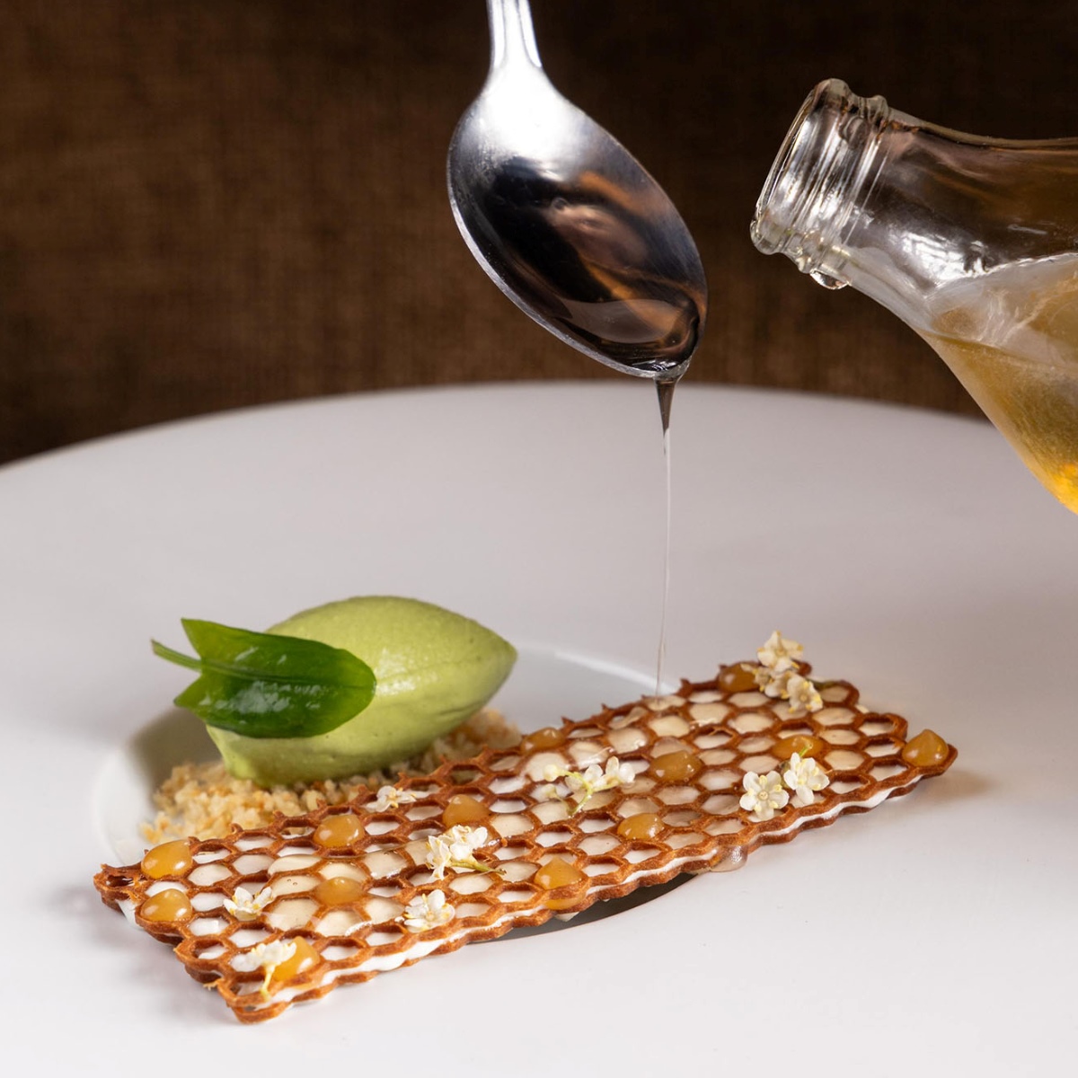 Nid d'abeille, sobremesa de mel de Mandaçaia, missô e azedinha, do restaurante Madame Olympe, que se une ao grupo de estabelecimentos com uma Estrela MICHELIN. © Madame Olympe