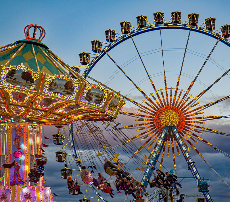 Eines der vielen Kettenkarussells und das große Riesenrad – das symbolischste aller Fahrgeschäfte auf der Wiesn © München Tourismus, Werner Boehm