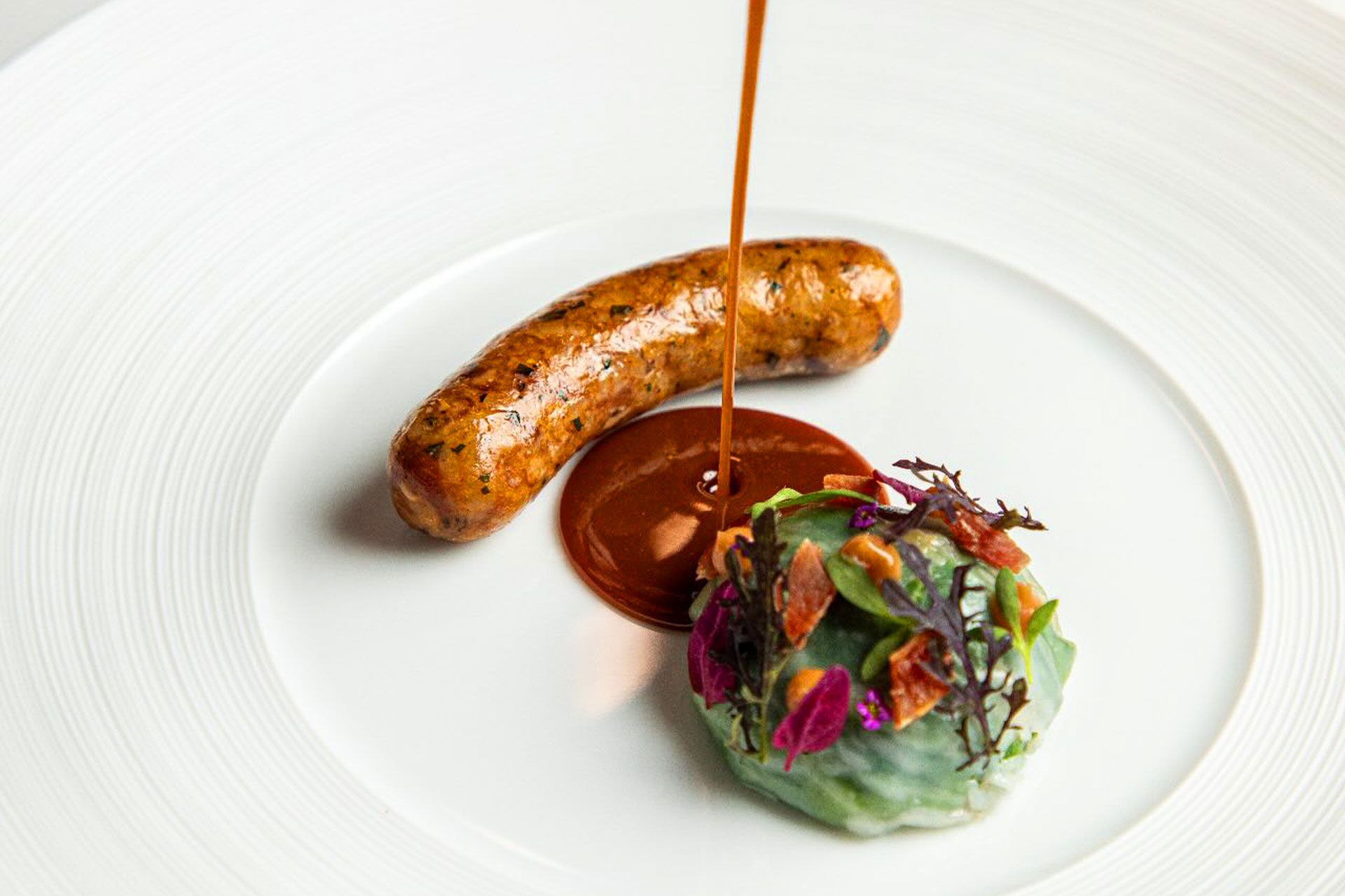 Boudin with collard greens, ham hock and Creole jus gras. © Randy Schmidt/Emeril’s