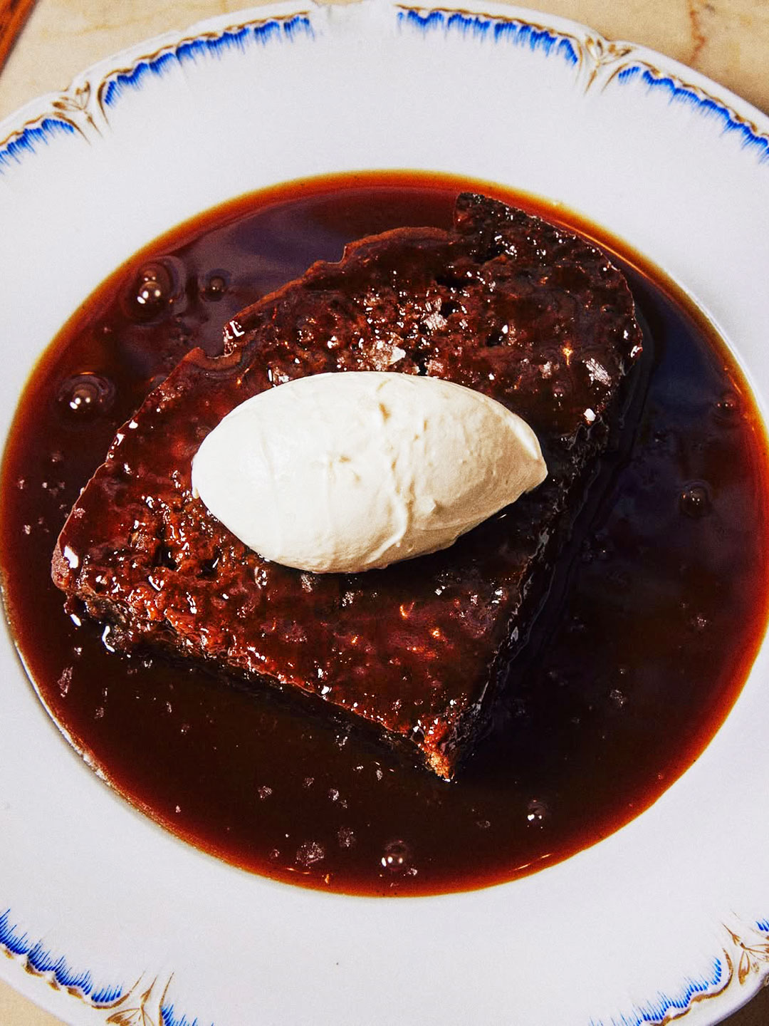Sticky toffee pudding with its warm brown sugar date cake with crispy edges, cloaked in bourbon caramel and finished with crème fraîche and Maldon salt. © Alex Lau/Dame