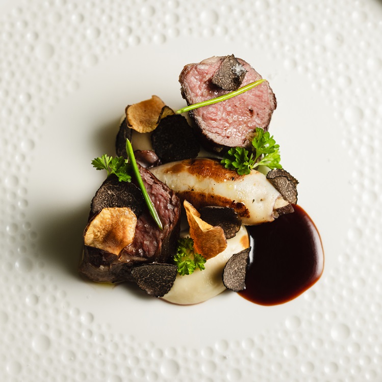 A refined dish of perfectly cooked meat with truffle, creamy purée, and rich jus, elegantly plated with crisp textures and fresh herbs. © Bistro Štorja