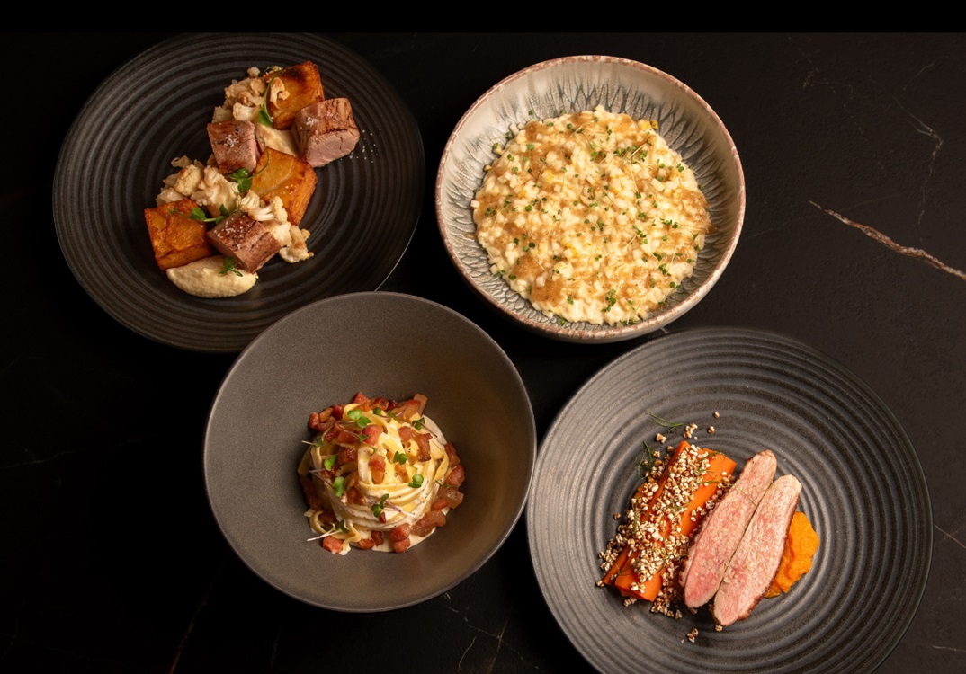 A refined selection of contemporary dishes plated with elegance, showcasing rich textures and vibrant colors on a dark marble table. © Bistro 9:45