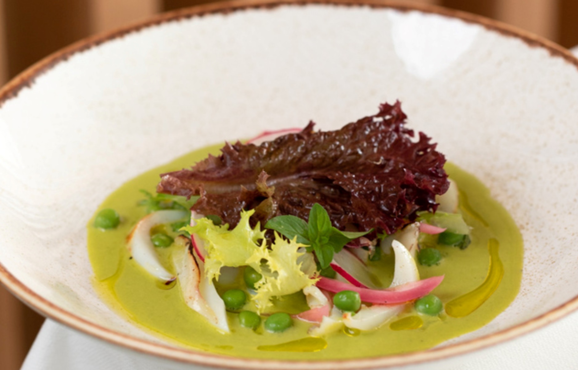 Un piatto che celebra l’orto e la stagionalità attraverso colori vivaci, consistenze delicate e un’elegante essenzialità. © Osteria Terra Arsa